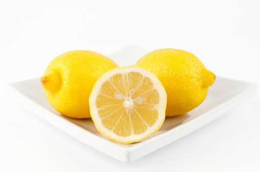 lemons on square plate yellow  porcelain white background cut in half  seeds Citrus fruit food