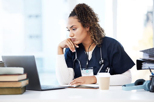 Healthcare, laptop and research with a woman nurse reading information in a hospital for diagnosis. Medical, insurance and education with a female med student working in a clinic for data analysis