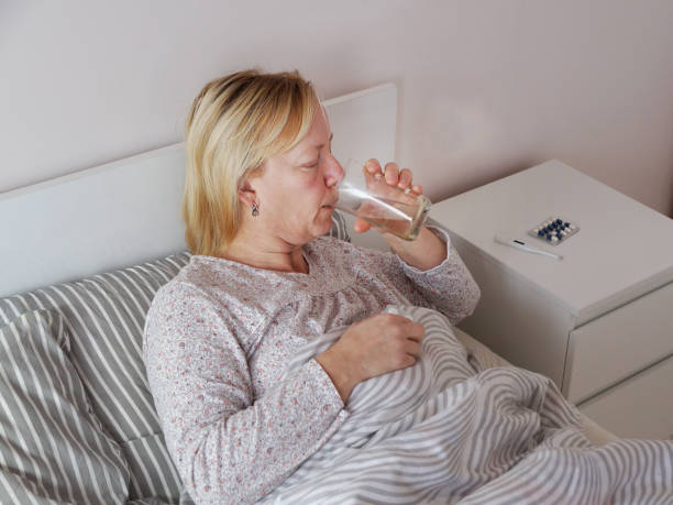 istock sick woman drinking medicine while lying in bed 1482827036