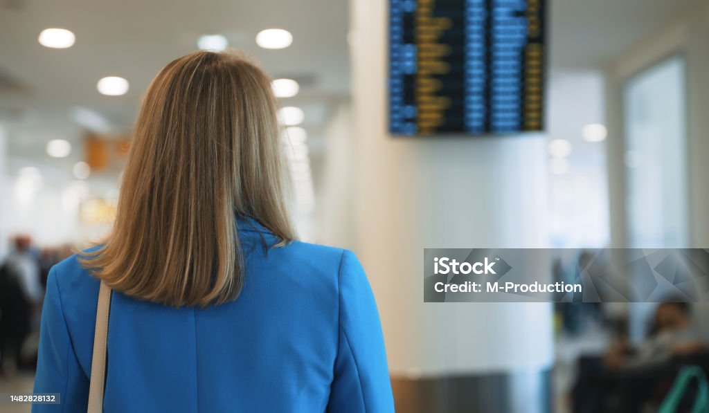 Woman in business suit in checking her flight in airport. 35-39 Years Stock Photo