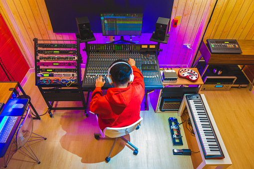 back of asian professional music producer working in recording studio. music production or post production concept