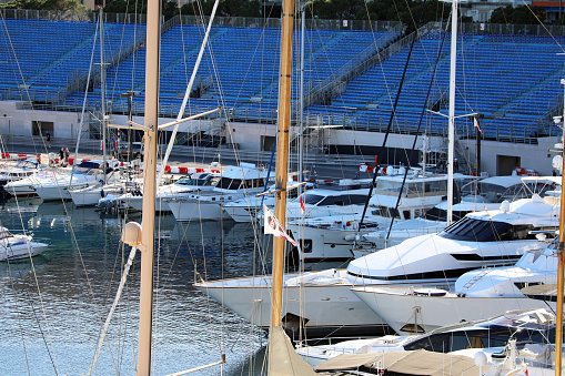 Monte-Carlo, Monaco - April 16, 2023: Numerous luxury boats and yachts at Port Hercule, Monte-Carlo, Monaco, with Formula 1 Grand Prix blue grandstands in the background