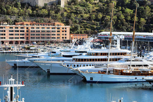 Monte-Carlo, Monaco - April 16, 2023: World's largest and most expensive superyachts tightly packed in Monte-Carlo, Monaco's port, with Formula 1 Grand Prix facilities in the background