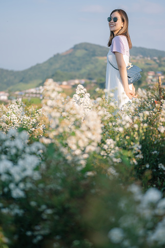 Young asian woman in white dress enjoying margaret flower blooming around she in mon jam chiang mai north of thailand