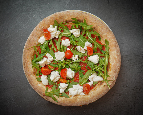 Feast your eyes on a close-up of a mouthwatering mozzarella tomato pizza, showcasing vibrant colors and a fragrant basil garnish. This homemade Italian cuisine offers a delightful combination of flavors, perfect for a delicious and satisfying meal.
