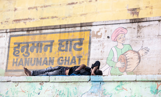 Varanasi, Uttar Pradesh, India - November 2022: Portrait of tourist resting on ghats near ganges in varanasi.