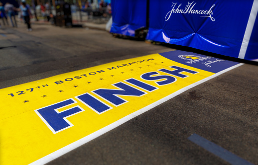 Boston, Massachusetts, USA - April 14, 2023: Wide angle view of the 127th Boston Marathon yellow Finish line across Boylston Street near Copley Square. The signature of John Hancock, an American Founding Father and prominent Patriot of the American Revolution. The marathon is always run on the Patriots Day holiday, April 17th for 2023.