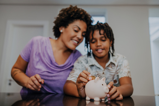Mother and son putting coin in piggy bank