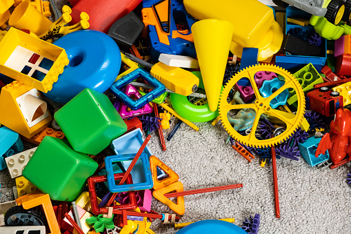 An abundance of toys in the children's room, a lot of plastic multi-colored parts from designers, spare parts for toys, figurines and cubes