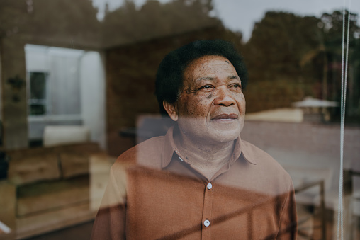 Portrait of a senior man looking through the window glass