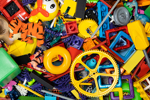 An abundance of toys in the children's room, a lot of plastic multi-colored parts from designers, spare parts for toys, figurines and cubes