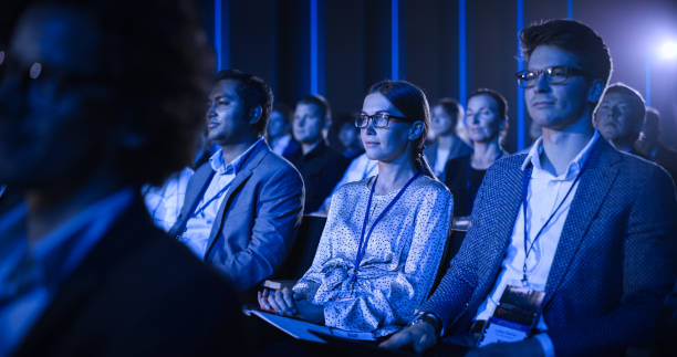 istock Young Female Sitting in a Crowded Audience at a Science Conference. Delegate Cheering and Applauding After an Inspirational Keynote Speech. Auditorium with Young Successful Specialist. 1482846241