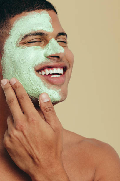 istock Man smiling as he cleanses his face with a green mask 1482846424