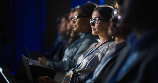 young psychologist attending an international cognitive behavioral therapy seminar. specialist using laptop computer. psychotherapy professional sitting in a crowded room on a training program. - üniversite seminer salonu stok fotoğraflar ve resimler