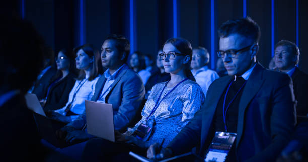 istock Young Woman Sitting in a Crowded Audience at a Business Conference. Female Delegate Using Laptop Computer. Manager Watching Inspirational Entrepreneurship Presentation About Developing Markets. 1482848072