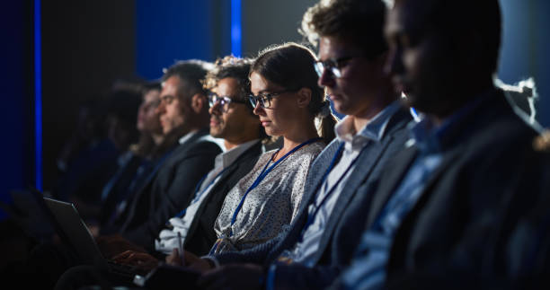 istock Young Woman Sitting in Crowded Audience at Human Resource Conference. Female Delegate Using Laptop Computer. HR Manager Listening to Inspirational Entrepreneurship Presentation About Social Studies. 1482848313