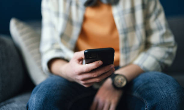 anonymous man sitting and using his mobile phone - homework teenager mobile phone school imagens e fotografias de stock