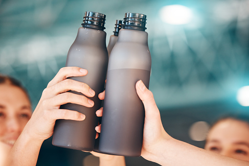 Hands, fitness and cheers with bottle water for team training, exercise or workout achievement in sports. Hand of sport group celebration touching bottles for drinking, hydration or winning in unity