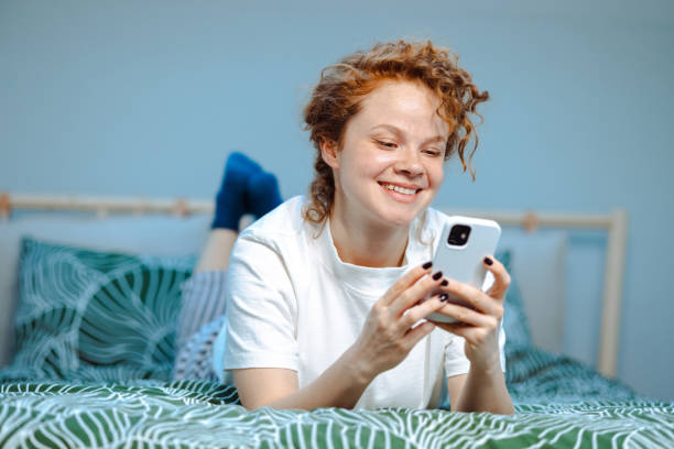istock Young woman in pajamas using smart phone in bed 1482851477