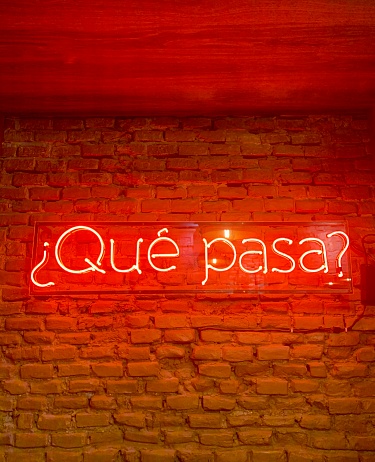 This is a shot of an indoor place where a Que Pasa Neon Sign brightens up the mood