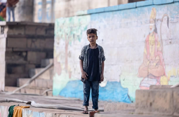Varanasi, Uttar Pradesh, India - November 20 2022: Portrait of Unidentified Indian holy boy standing on ghats near river ganges in varanasi city in traditional dress.