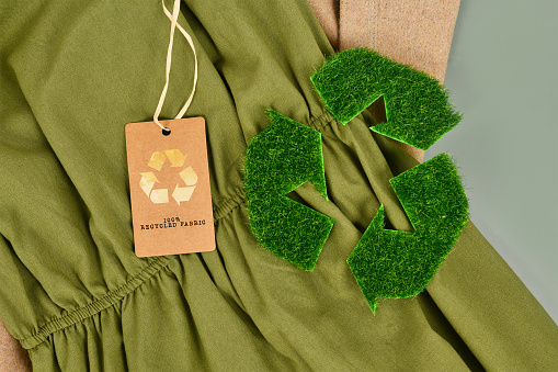 Green and beige eco friendly cotton fabric with 100 percent recycled label and recycling symbol made out of grass