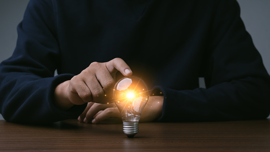 Creative thinking idea for Tecnology concept.Hand of businessman touching light bulb with orange glowing and keyboard.Creative thinking idea concept.