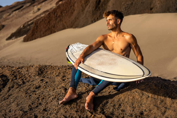 istock Smiling young man with surfboard on the beach. 1482858536