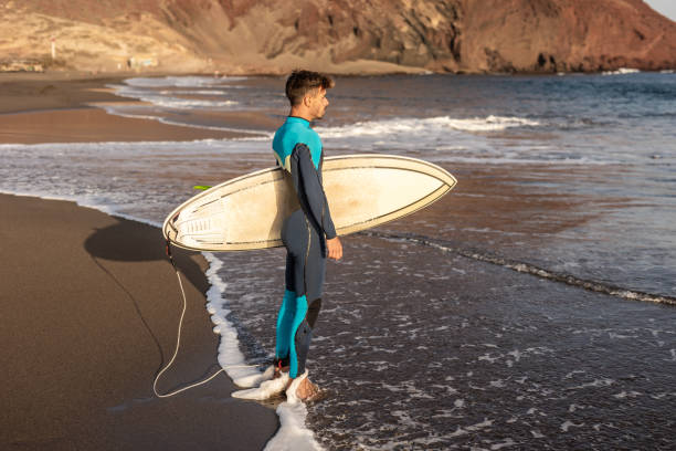 istock A surfer walks along a sandy beach and carries a surfboard in his hands 1482858592