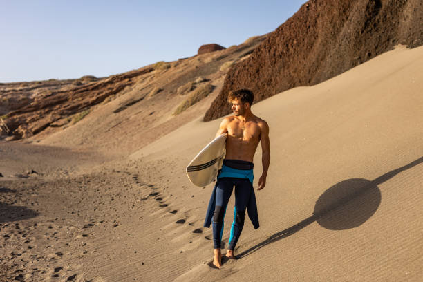 istock Smiling young man with surfboard on the beach. 1482858617