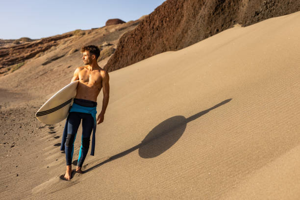 istock Smiling young man with surfboard on the beach. 1482858623