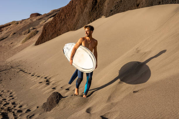 istock Smiling young man with surfboard on the beach. 1482858626