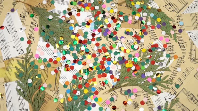 Colorful confetti, dried branches of an evergreen tree and collage of pieces of old sheet music, christmas background