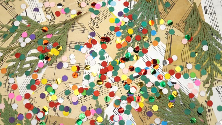 Colorful confetti, dried branches of an evergreen tree and collage of pieces of old sheet music, christmas background