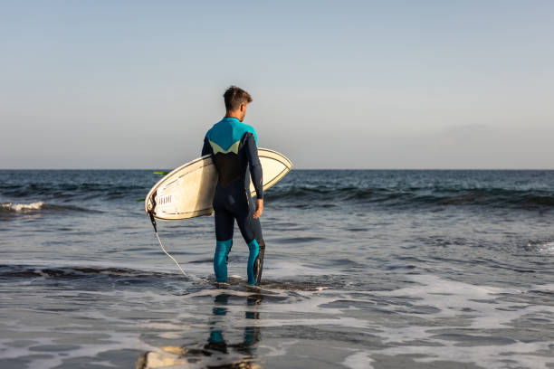 istock A surfer walks along a sandy beach and carries a surfboard in his hands 1482862297