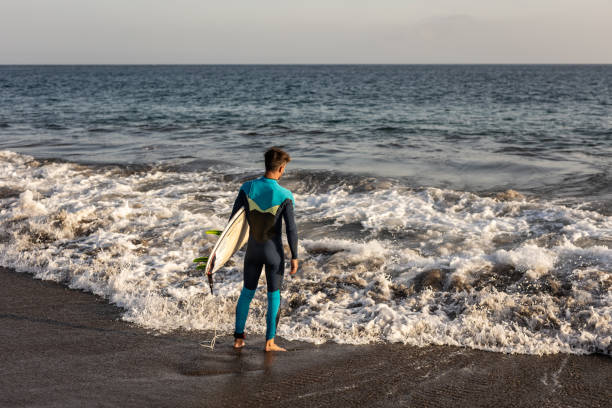 istock A surfer walks along a sandy beach and carries a surfboard in his hands 1482862344