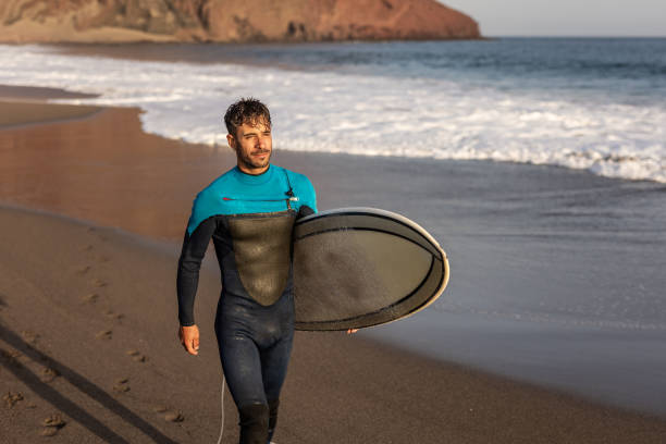 istock A surfer walks along a sandy beach and carries a surfboard in his hands 1482863593