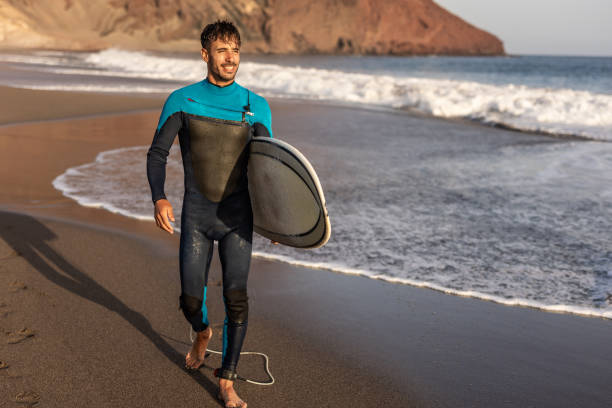 istock A surfer walks along a sandy beach and carries a surfboard in his hands 1482863596