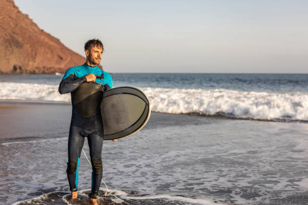 istock A surfer walks along a sandy beach and carries a surfboard in his hands 1482863600