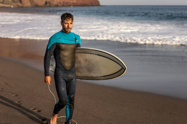 istock A surfer walks along a sandy beach and carries a surfboard in his hands 1482863602