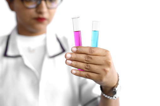 Young female chemist in formal wear conducting scientific experiment using chemicals in a laboratory.