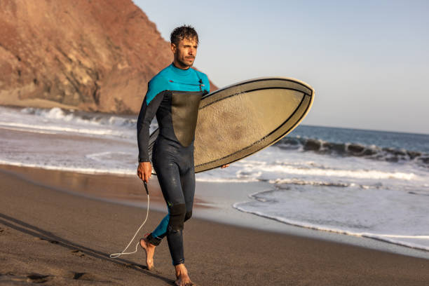 istock A surfer walks along a sandy beach and carries a surfboard in his hands 1482864618