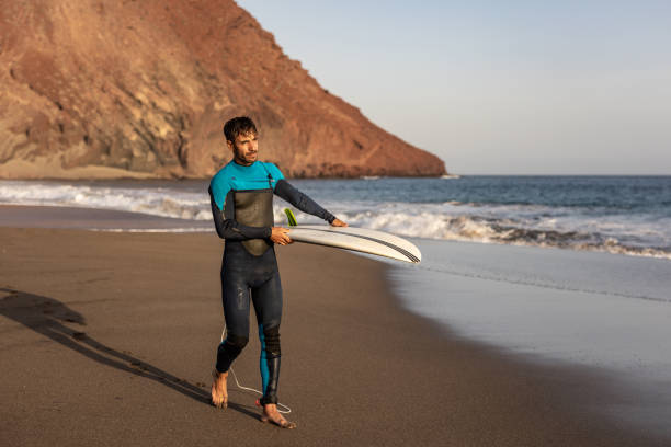 istock A surfer walks along a sandy beach and carries a surfboard in his hands 1482864636