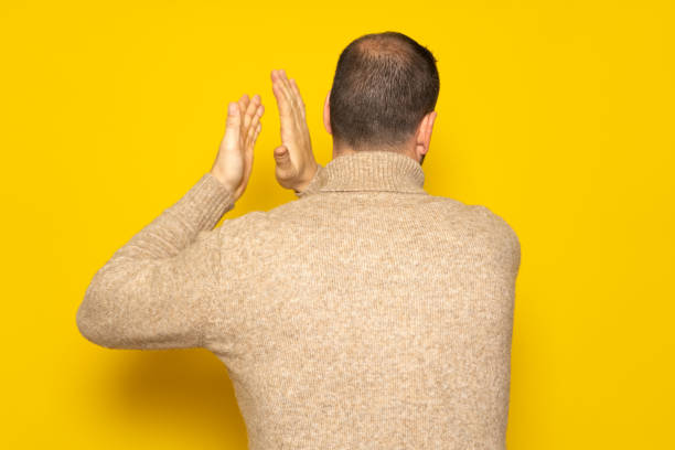 istock Man with alopecia problem energetically patting his back, excited by the spectacle he has just witnessed. Isolated on yellow background 1482865775