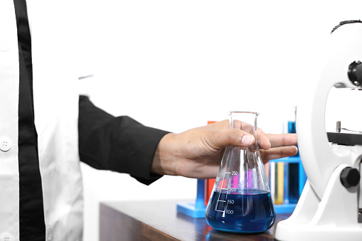 Young woman in lab wear conducting scientific experiment using chemicals and laboratory equipment.