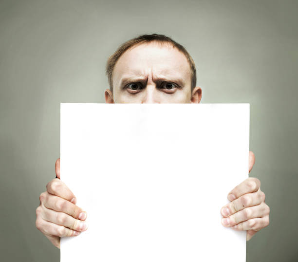 istock Young frowning man holding blank sign paper 1482870862