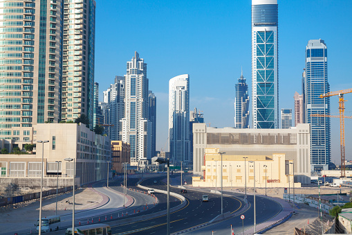 Cityscape of Dubai near Dubai Mall seen from skytrain and station and pedestrian footbridge. On street some traffic is ruling in early morning