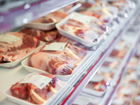 Packaged pork meat displayed on shelves of animal products section of supermarket