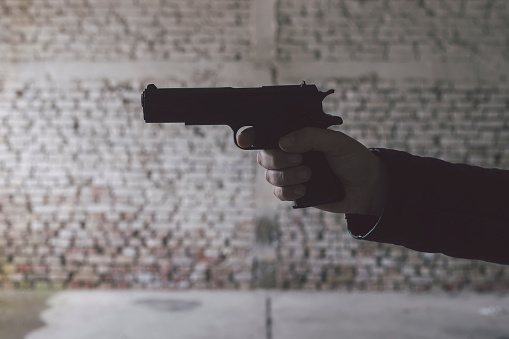 Adult man with gun at dark spooky building. Actor-model performing.