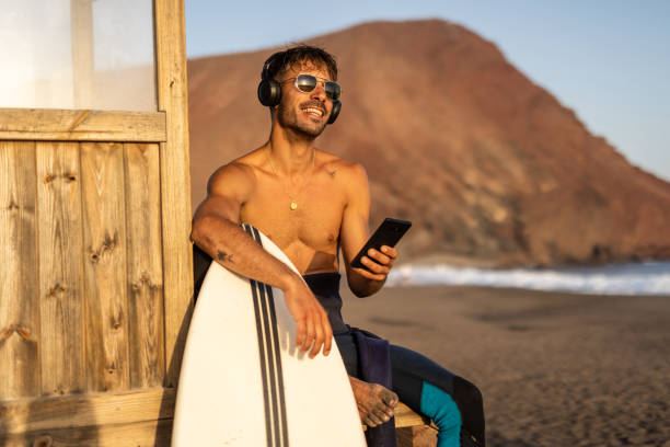 istock Surfer with a surfboard on the shore, sitting on an observation deck and taking a break from surfing the waves or waiting for a new opportunity to enjoy surfing 1482877927